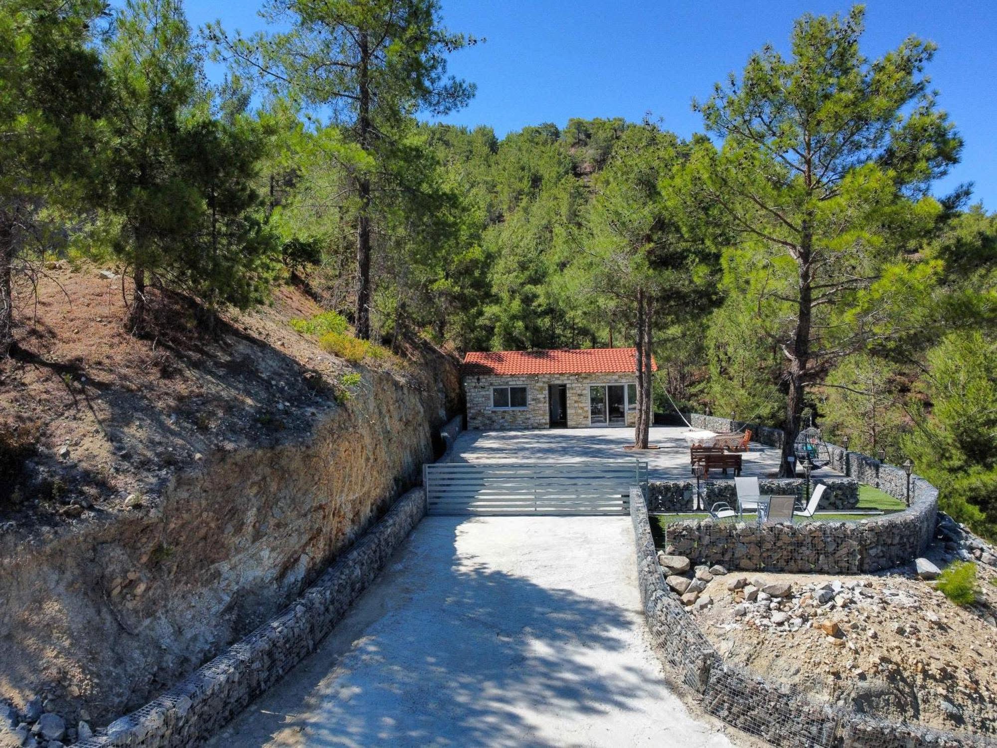 The private concrete drive climbing between gabion stone walls to the residence and its terrace
